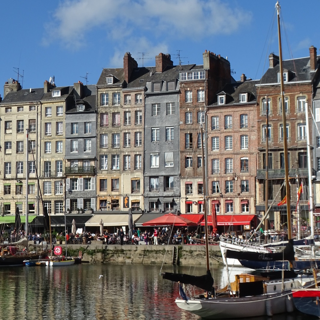 Le port historique de Honfleur avec de nombreux bateaux et de hautes maisons étroites à l'arrière